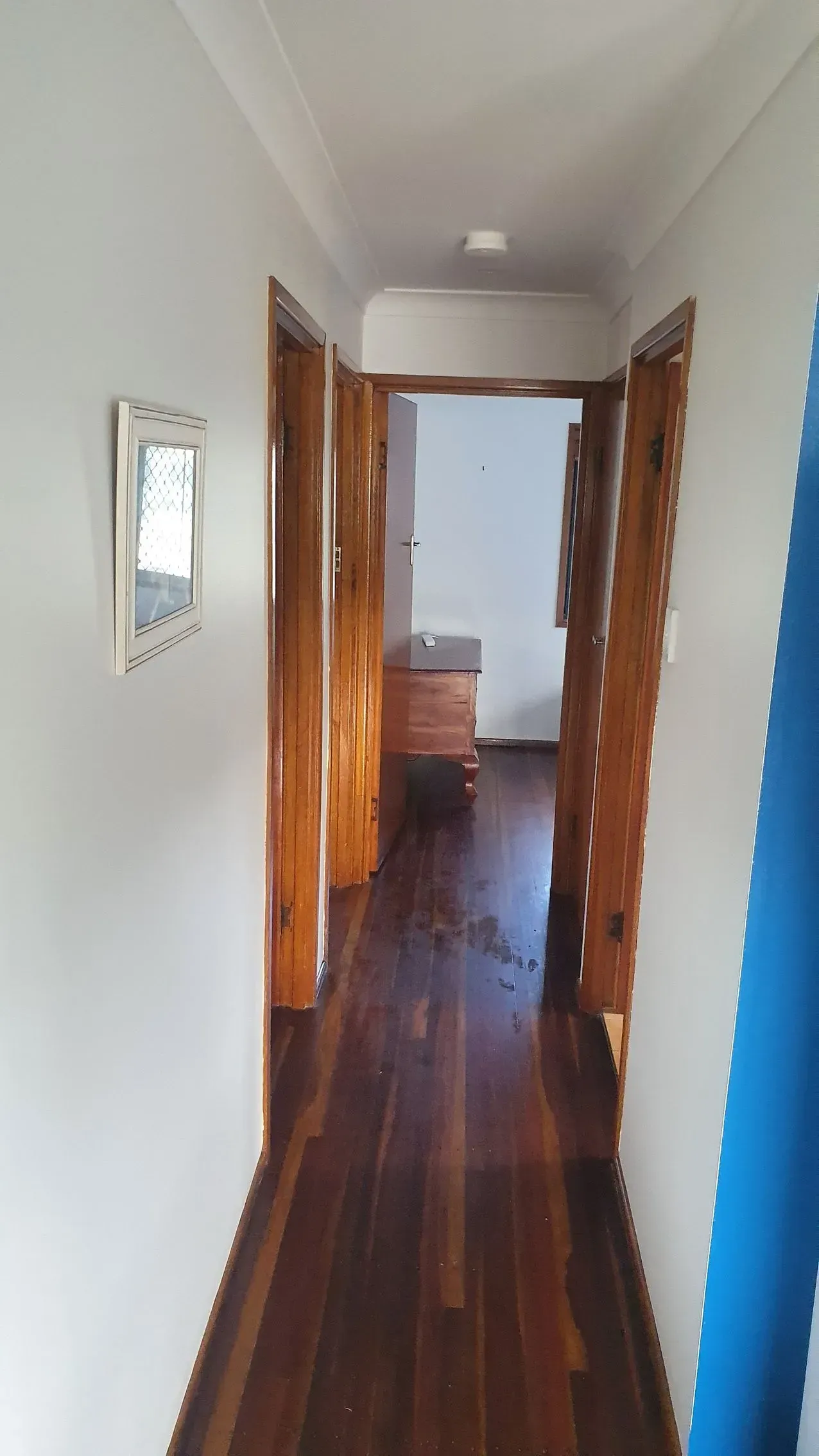 Hallway With Wooden Floors and Doors, White Walls, and a Mirror — Keppel Coatings in Pacific Heights, QLD