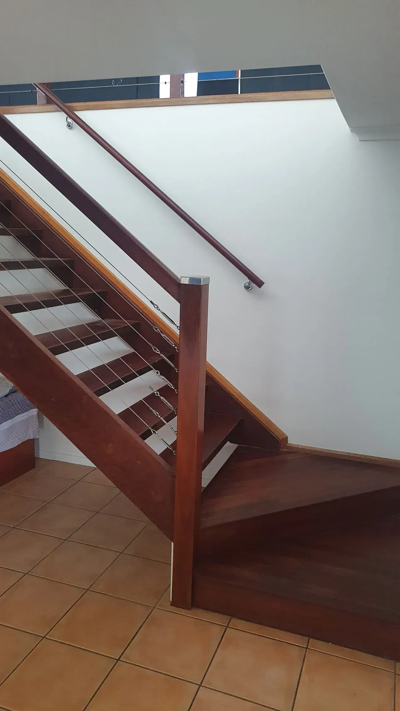 Wooden Staircase With a Dark Banister Ascending Against a White Wall — Keppel Coatings in Pacific Heights, QLD
