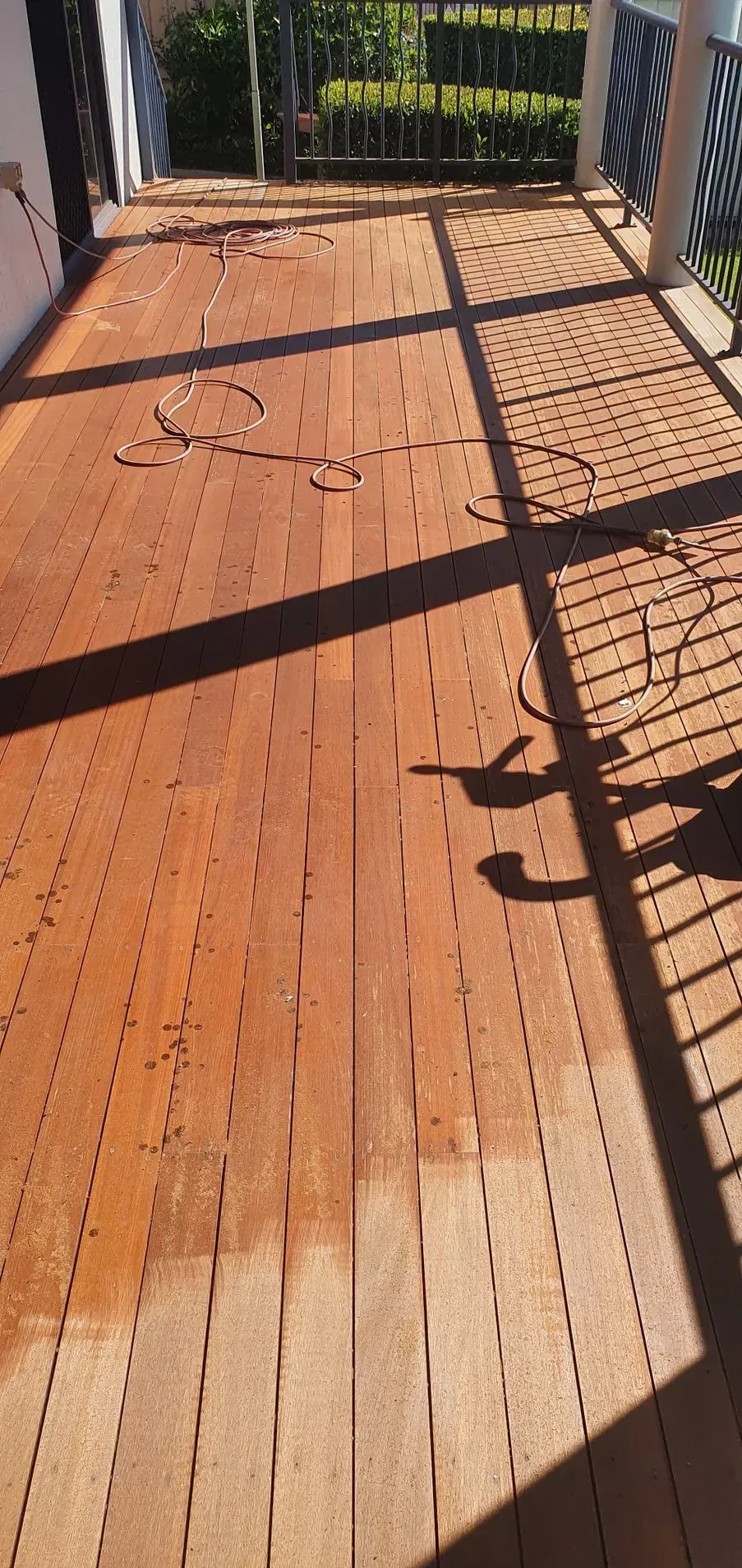 Wooden Deck Being Cleaned. Half of the Deck is Wet — Keppel Coatings in Pacific Heights, QLD