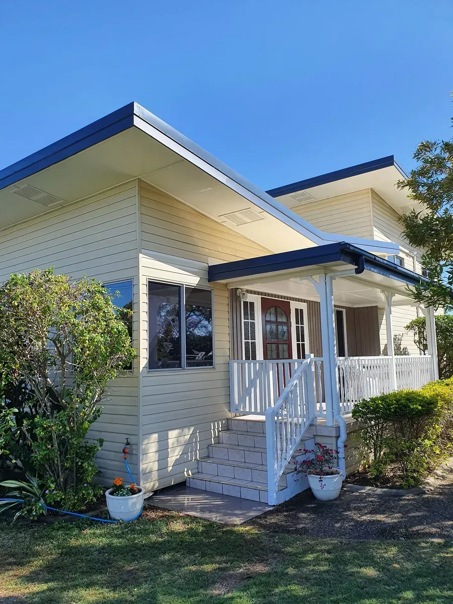 Yellow House With White Porch and Blue Roof — Keppel Coatings in Pacific Heights, QLD