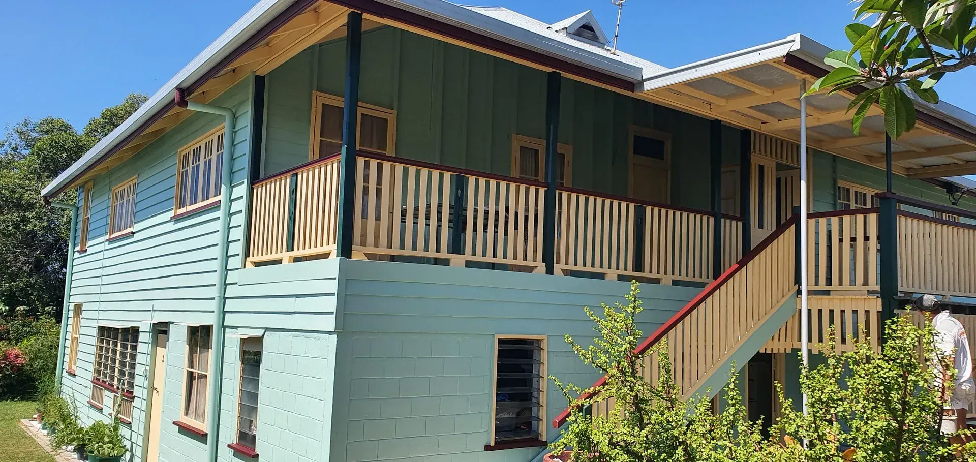 Two-story Blue House With Green Trim and a Wrap-around Porch — Keppel Coatings in Pacific Heights, QLD