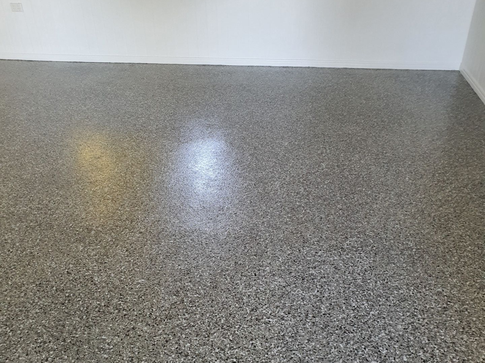 Interior wall covered in textured, speckled gray and white aggregate.— Keppel Coatings in Pacific Heights, QLD