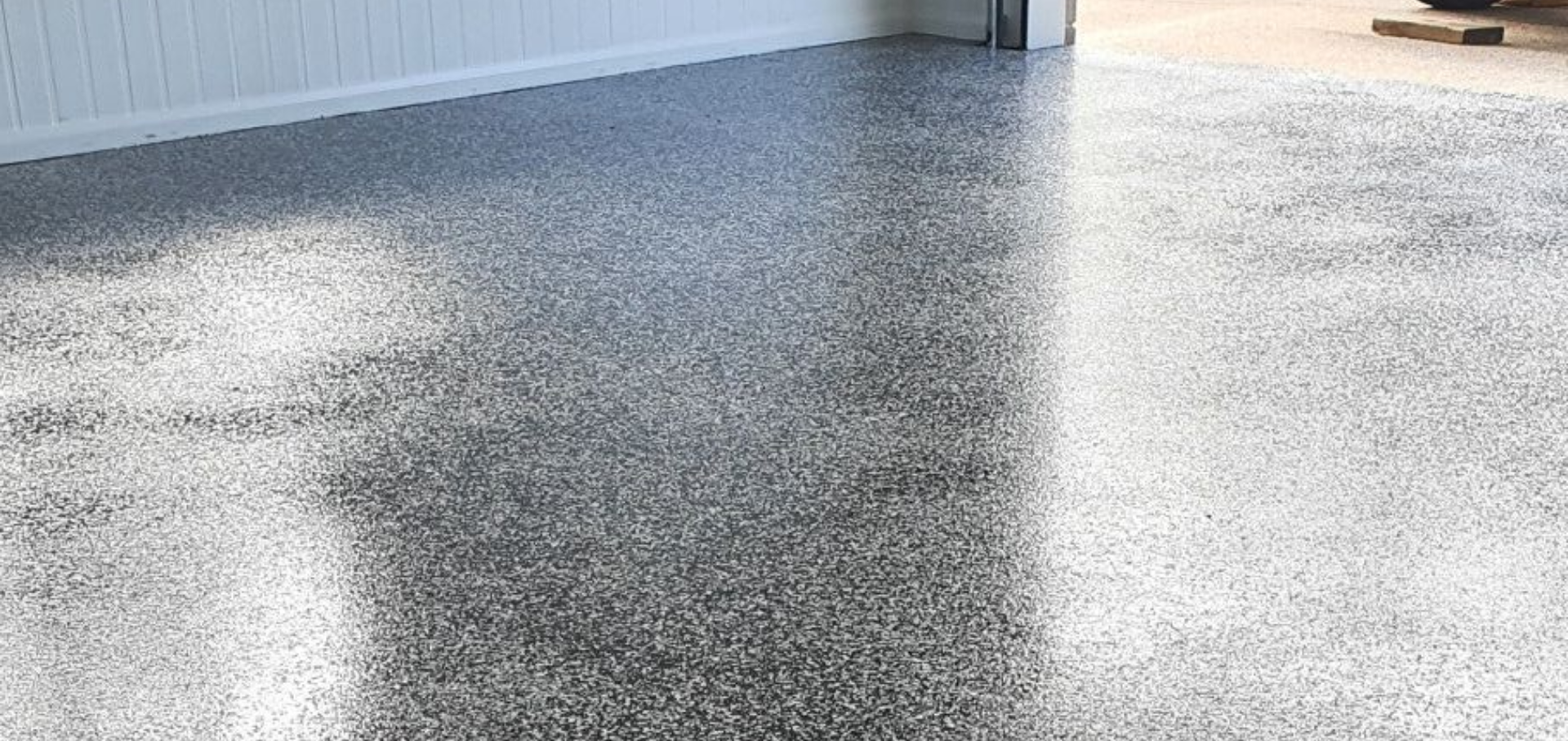 Gray speckled epoxy floor. White wall on the left, open doorway on the right.— Keppel Coatings in Pacific Heights, QLD