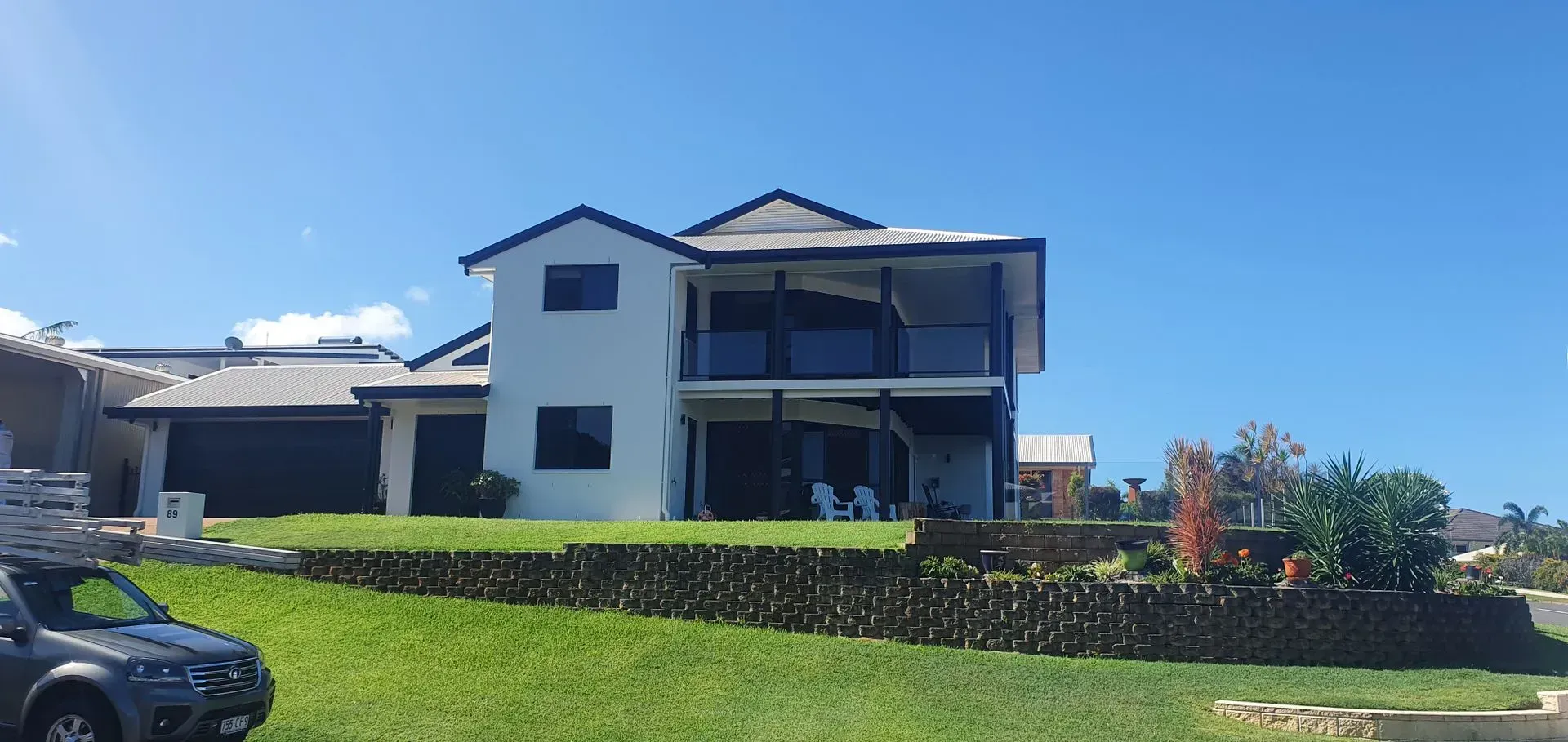 Two-story White House With Black Trim, Balcony, and a Grassy Yard — Keppel Coatings in Pacific Heights, QLD