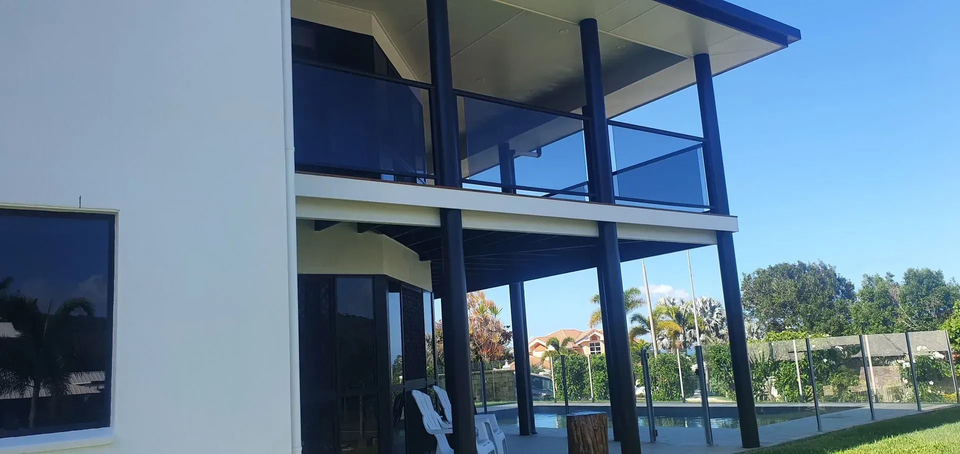 Two-story House With Glass Balconies, Black Pillars, and a Blue Sky — Keppel Coatings in Pacific Heights, QLD