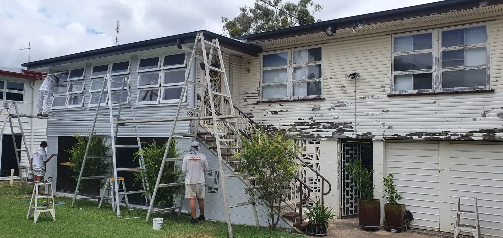 Workers Painting a Two-story White House With Several Ladders — Keppel Coatings in Pacific Heights, QLD