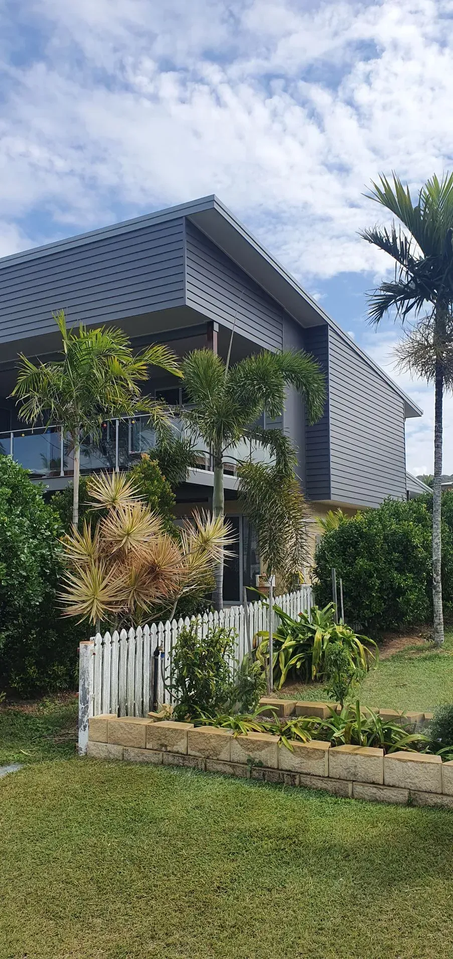 Modern House With a Slanted Roof, Glass Balconies, and Tropical Landscaping — Keppel Coatings in Pacific Heights, QLD