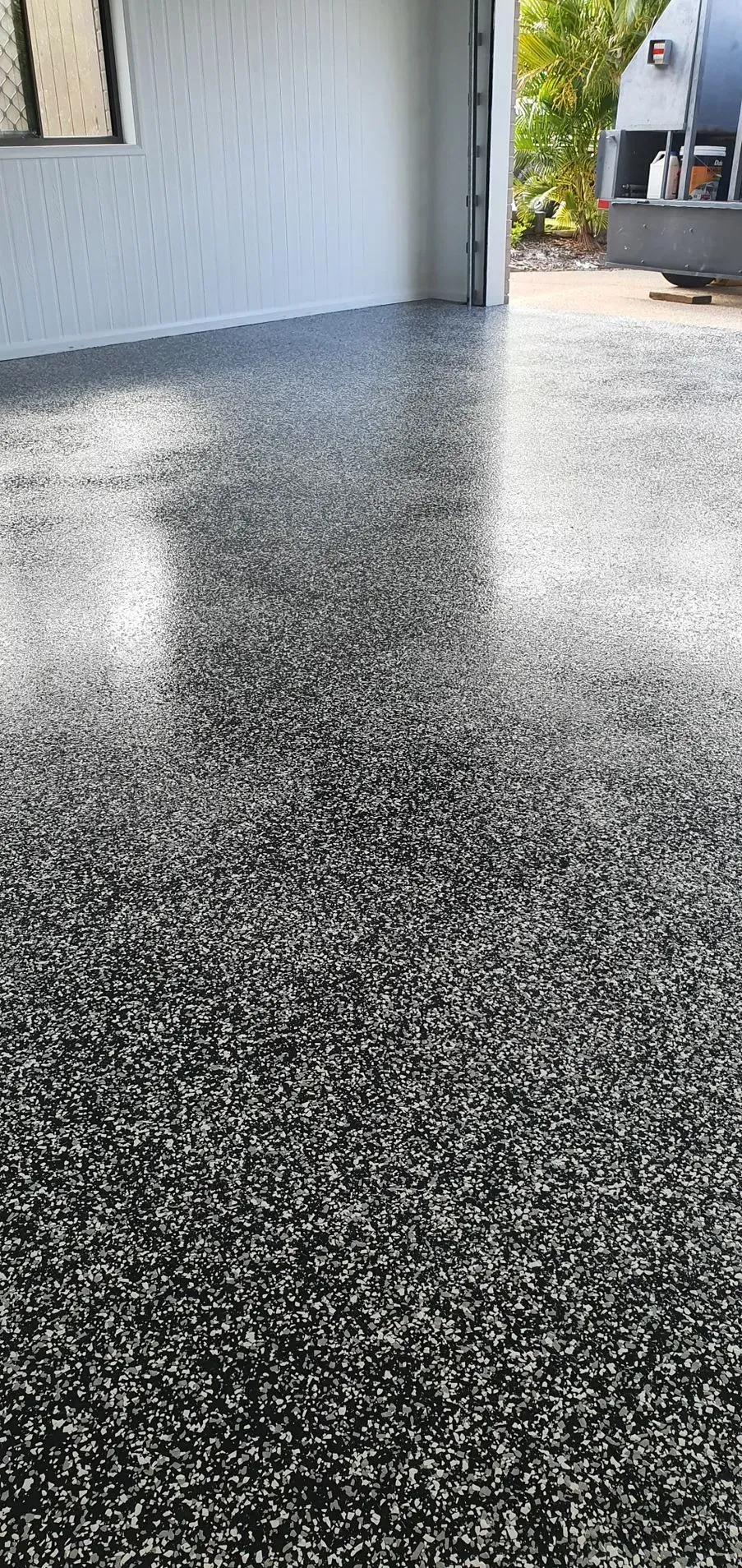 A Speckled Epoxy Floor Reflects Light. the Floor is in an Outdoor Space — Keppel Coatings in Pacific Heights, QLD