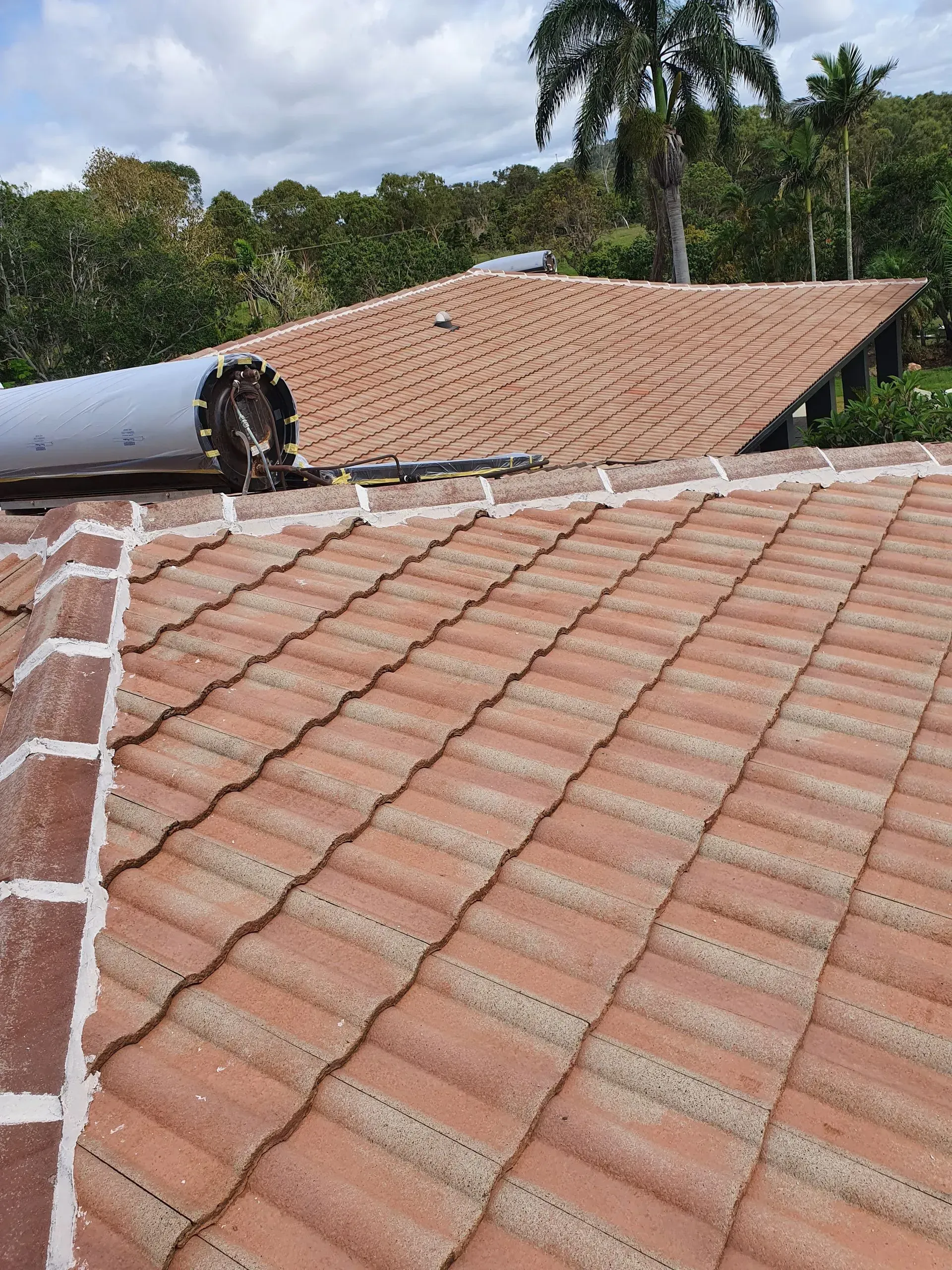 Clay Tile Roof With Solar Panel, Overlooking a Tree-filled Landscape — Keppel Coatings in Pacific Heights, QLD