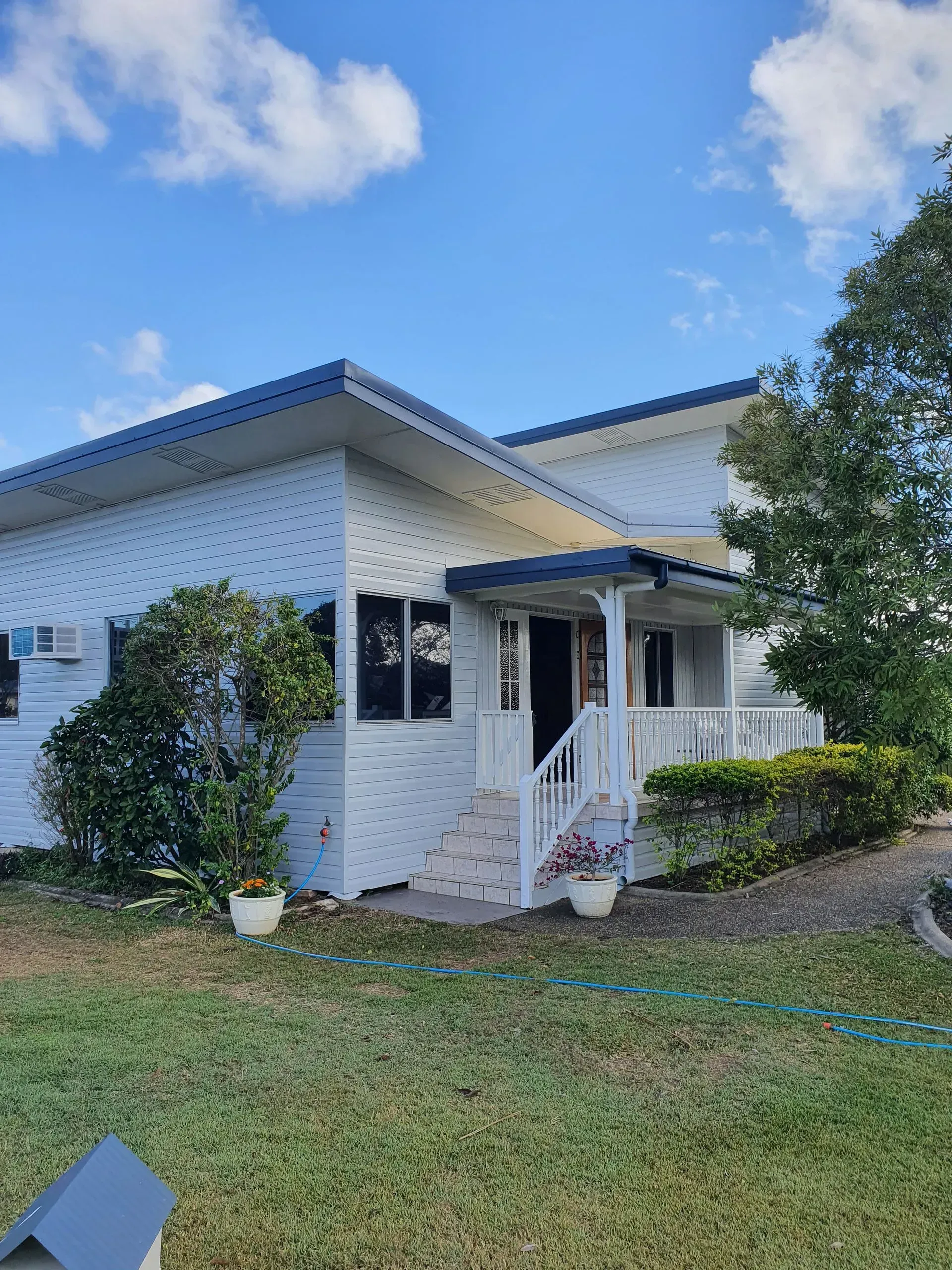 White House With Blue Roof, Porch, and Landscaping — Keppel Coatings in Pacific Heights, QLD
