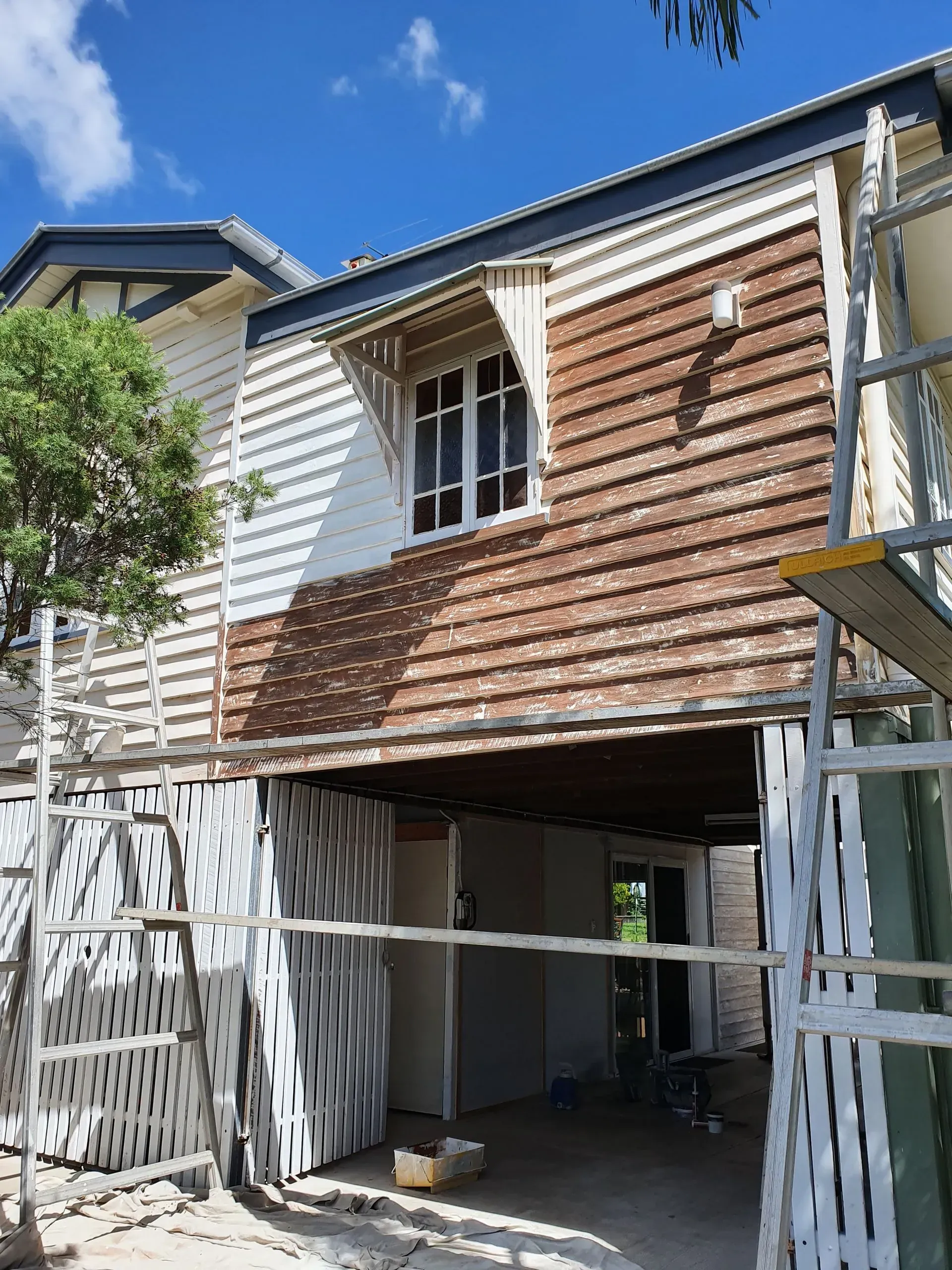 Exterior House Under Renovation With Scaffolding and Exposed Siding — Keppel Coatings in Pacific Heights, QLD