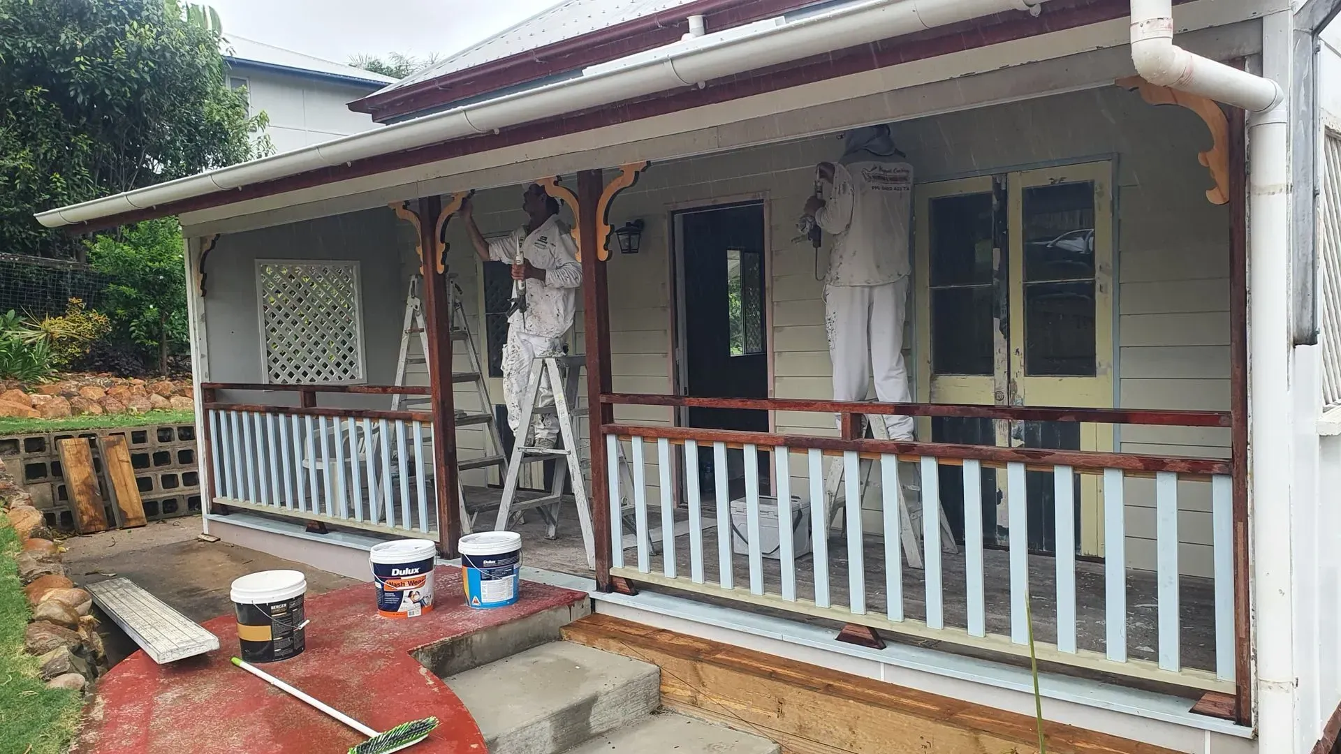 Two Painters in Coveralls Paint a Porch — Keppel Coatings in Pacific Heights, QLD