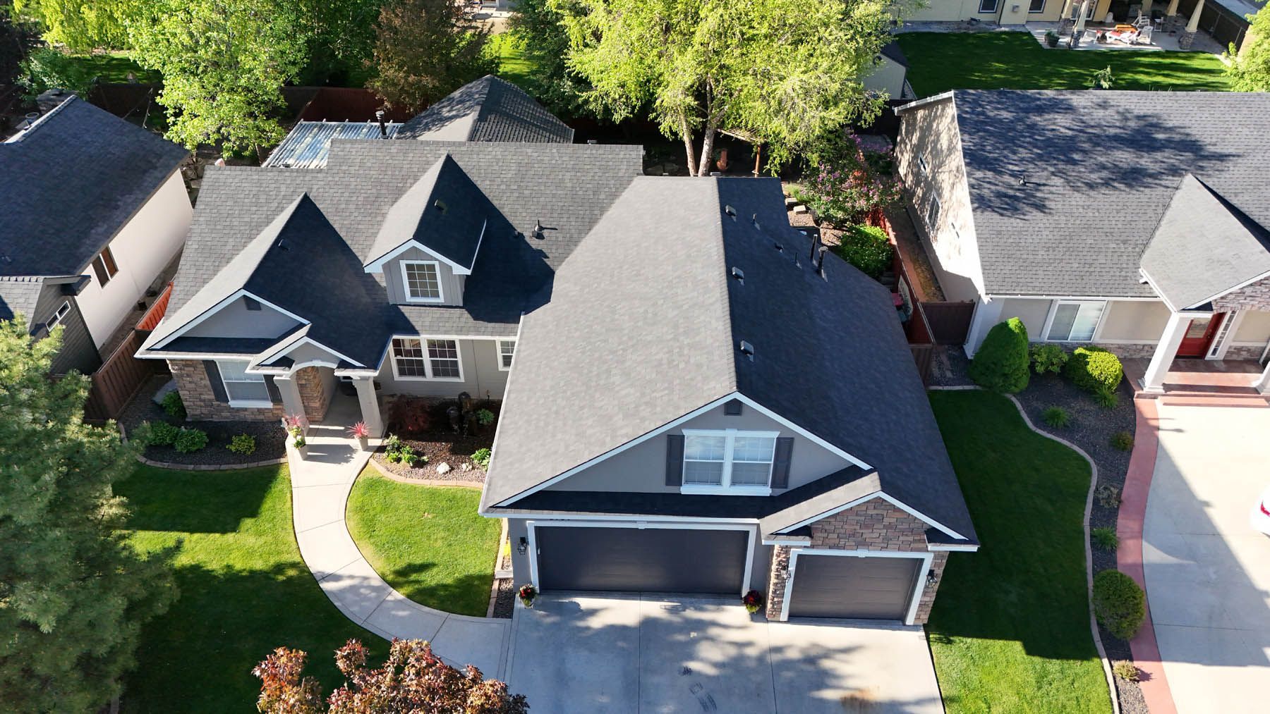 Aerial view of a two-story house with a dark gray roof and siding, two-car garage, and green lawn.