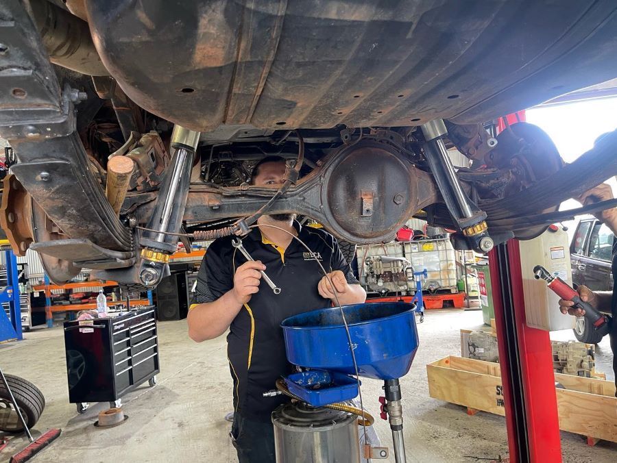 A Man is Working on the Underside of a Car in a Garage — E.C.A Mechanical Repairs in Paget, QLD