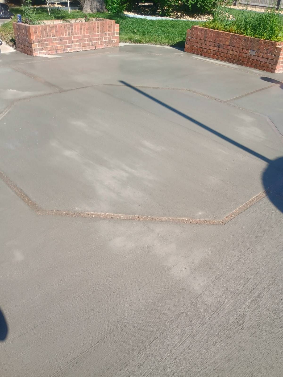 Concrete patio with brick planters and long shadows in sunlight