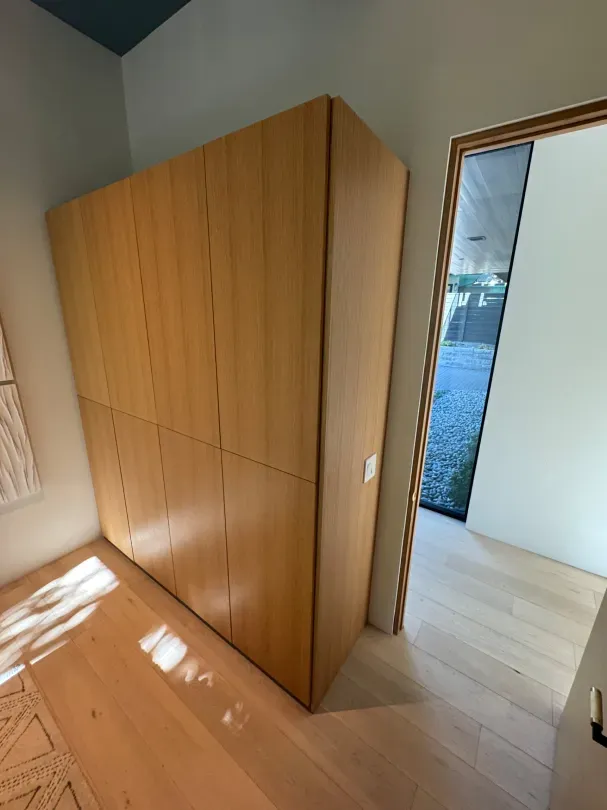 A room with a large wooden cabinet and a door leading to a bedroom