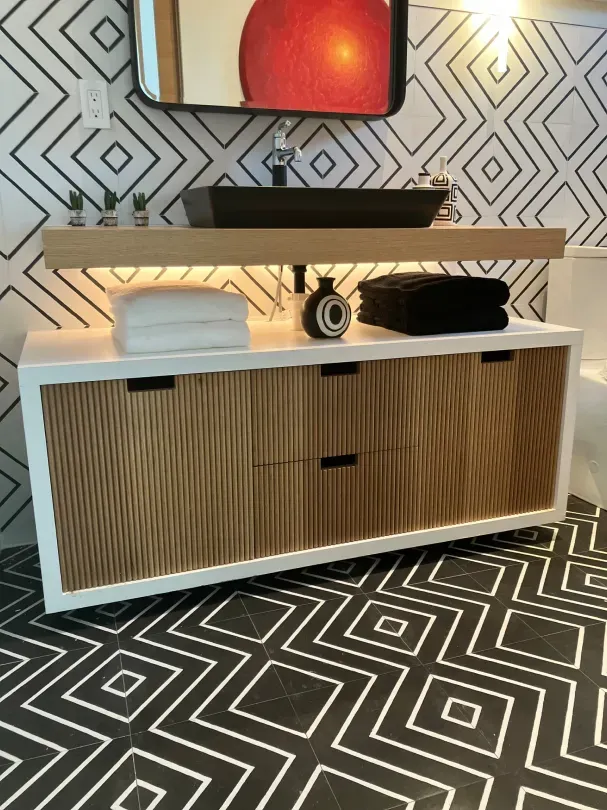 A bathroom with a wooden vanity and a black sink