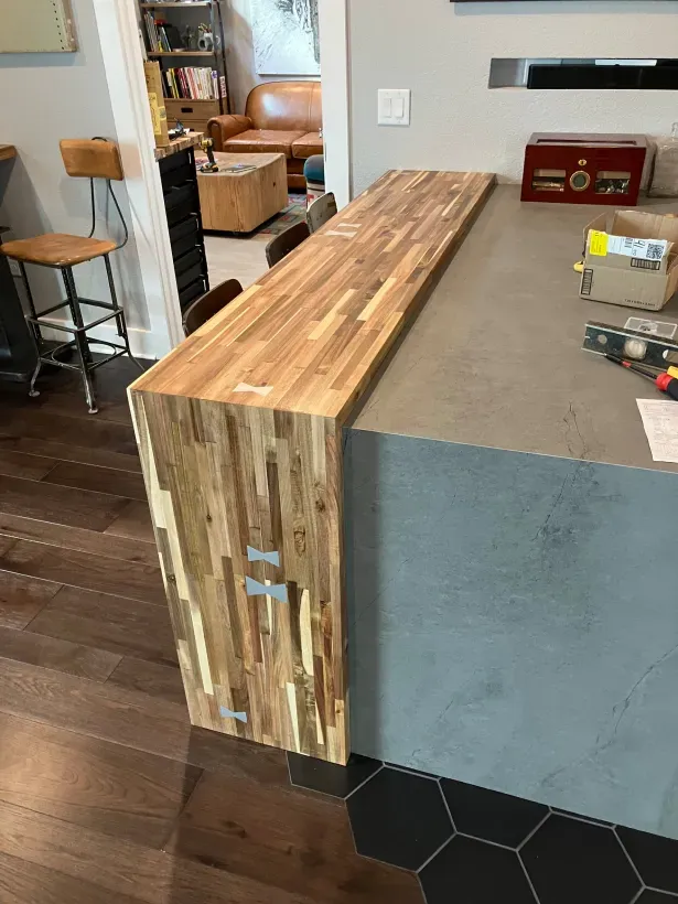 A wooden counter top is sitting on top of a concrete counter in a kitchen.