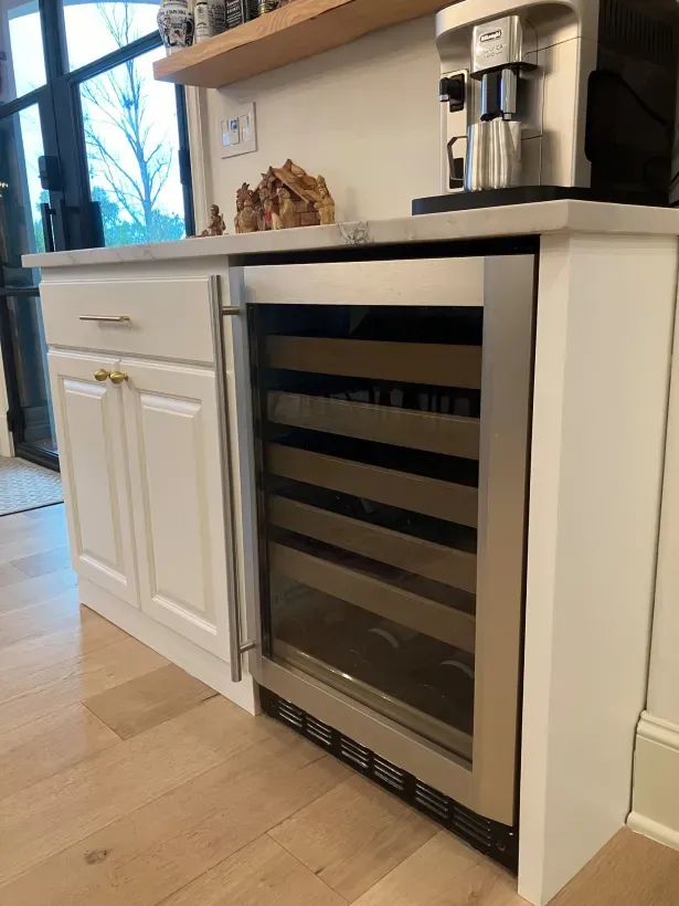 A wine cooler is sitting on top of a counter in a kitchen.