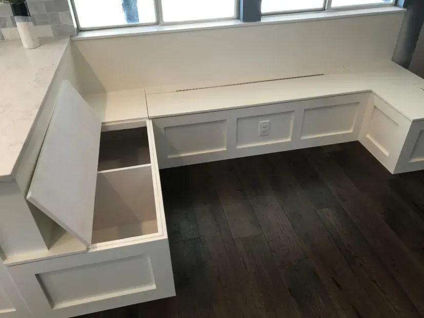A white l shaped bench with storage underneath it in a kitchen.