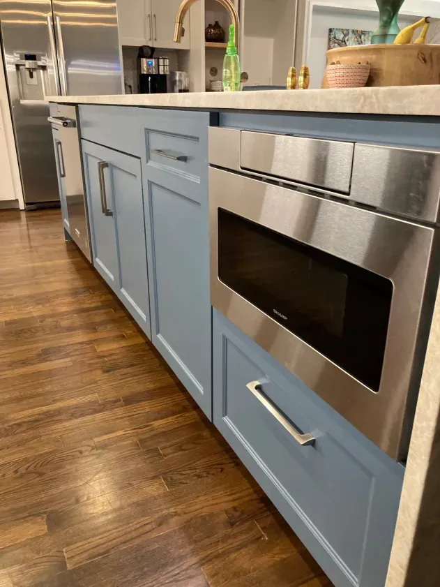 A kitchen with blue cabinets and stainless steel appliances.