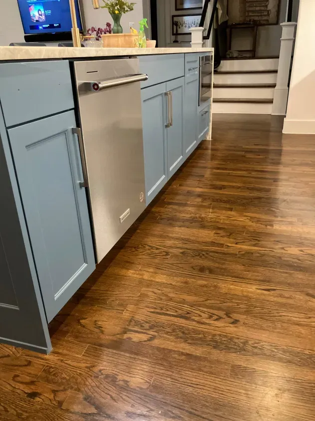 A kitchen with blue cabinets and a stainless steel dishwasher.