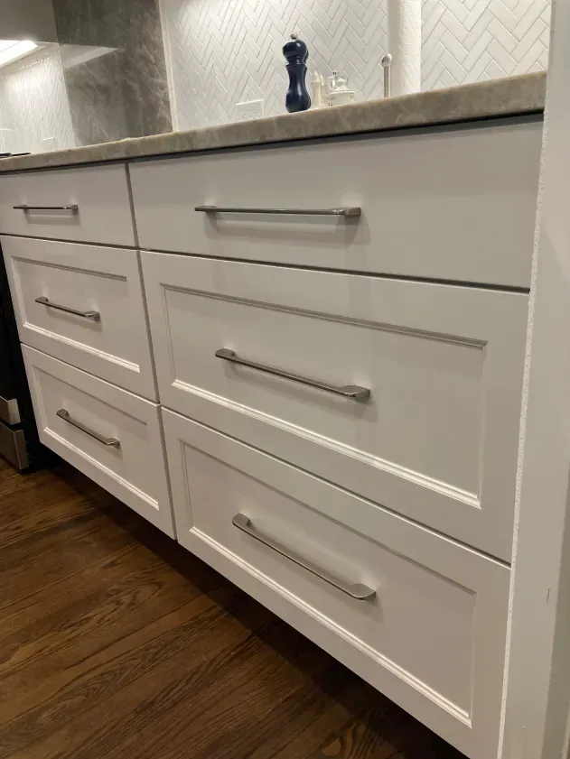 A kitchen with white cabinets and a marble counter top.