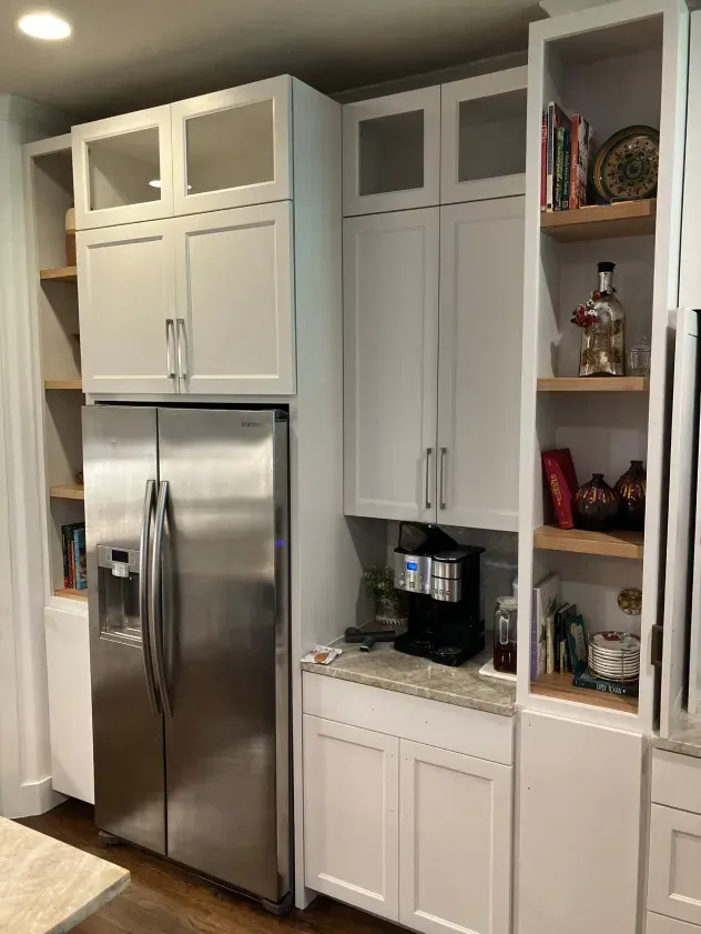 A kitchen with white cabinets and a stainless steel refrigerator.