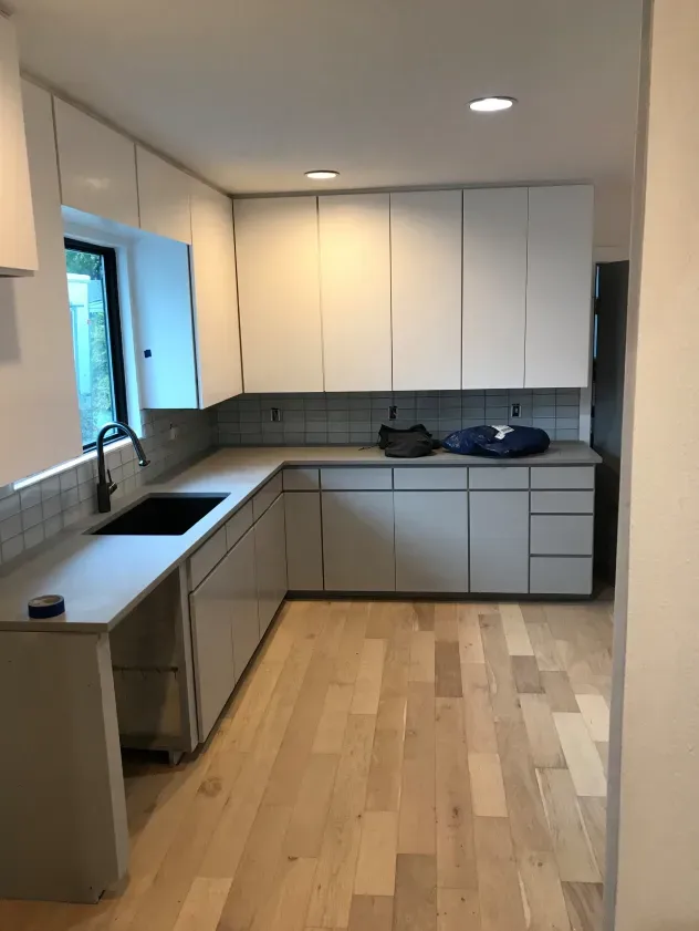 A kitchen with white cabinets and wooden floors