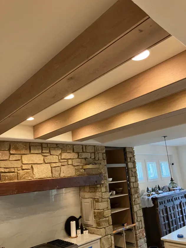 A kitchen with wooden beams and a stone wall