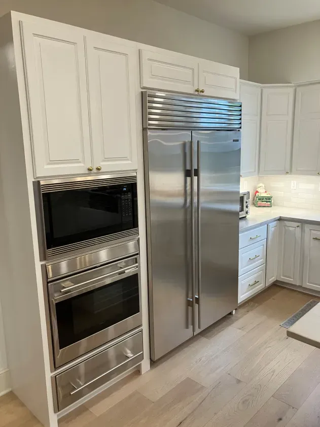 A kitchen with stainless steel appliances and white cabinets.