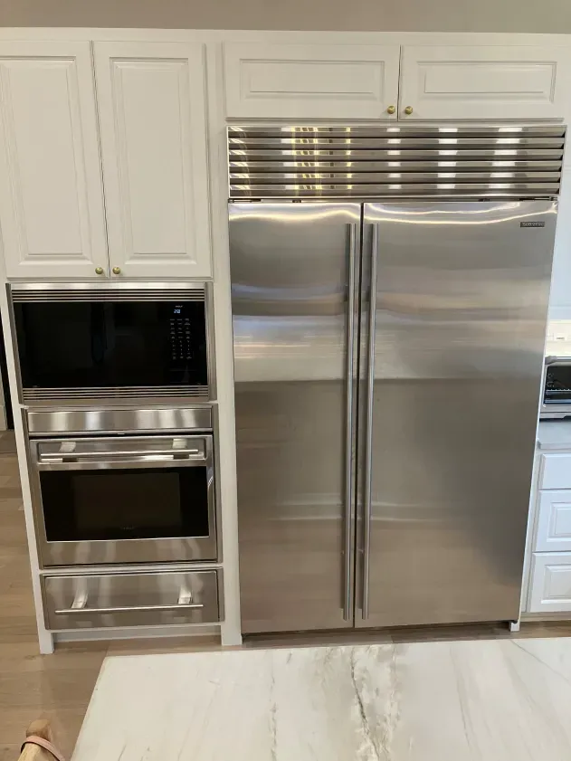 A stainless steel refrigerator and microwave are in a kitchen