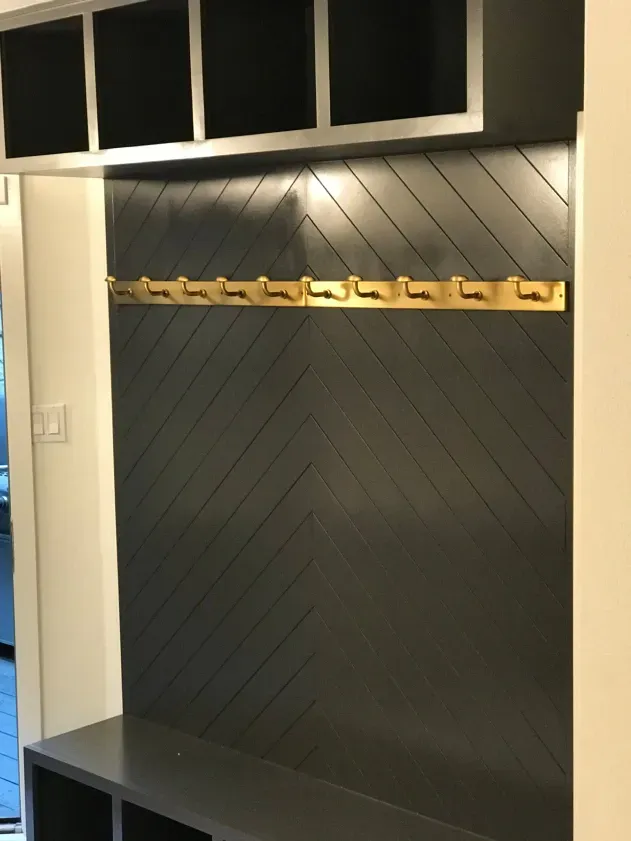 A black wall with a shelf and hooks on it