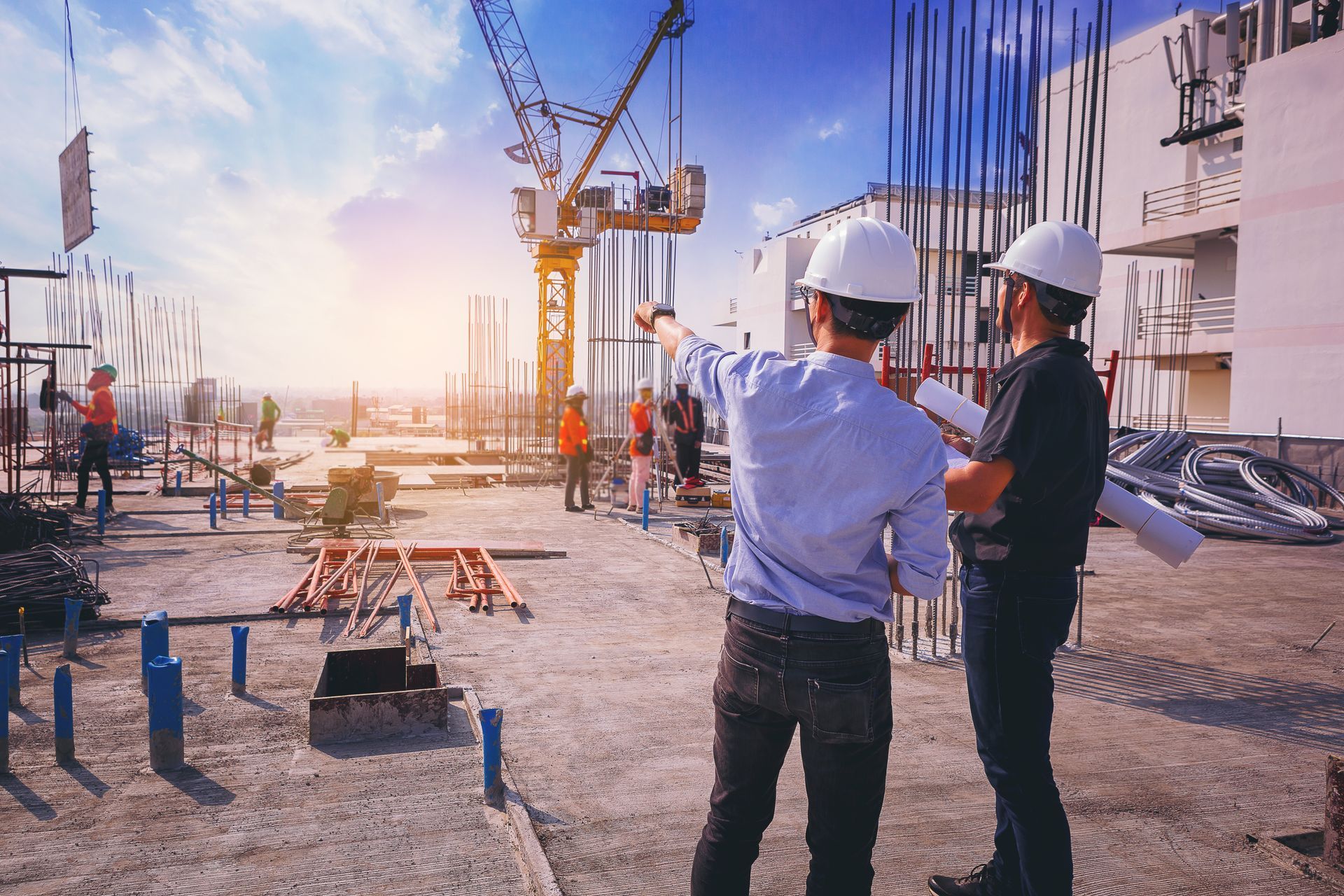 Two construction workers are looking at a blueprint at a construction site.