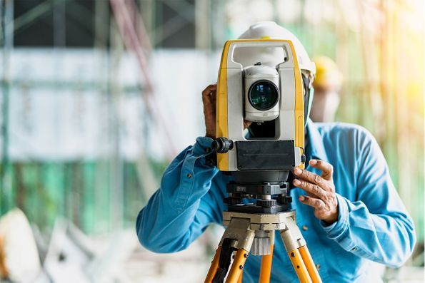 A man is using a theodolite on a construction site.