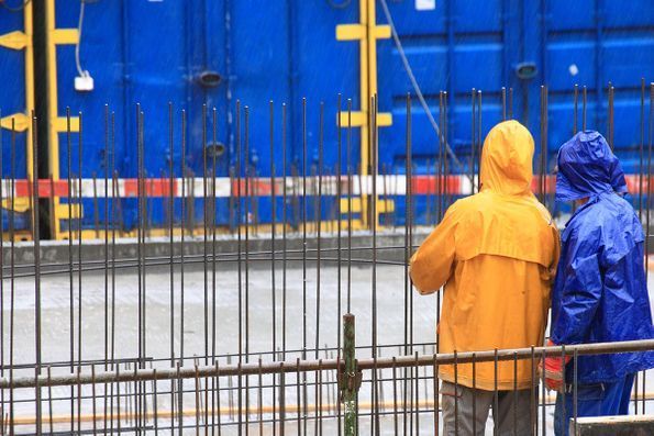 Two construction workers are standing next to each other on a construction site.
