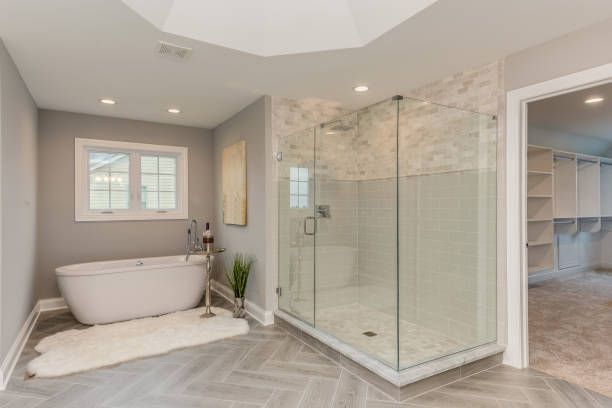 Spacious bathroom with gray walls, white soaking tub, glass shower, and walk-in closet.