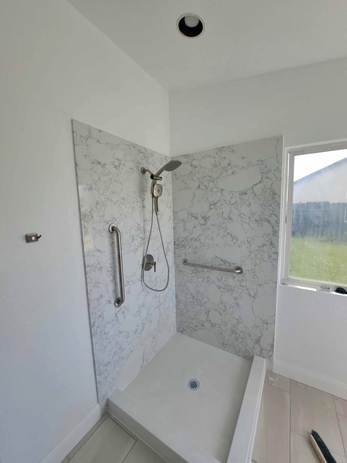 Shower with marble-look wall panels, grab bars, and a low threshold entry.