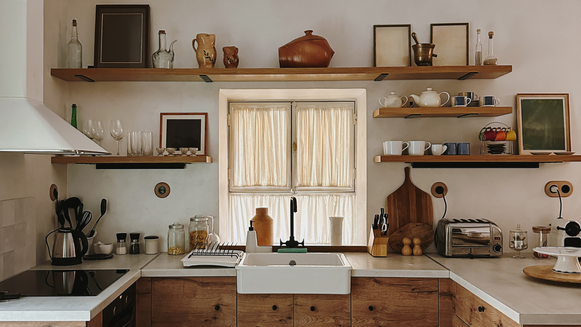 Rustic kitchen with open wooden shelves, a window with curtains, and a farmhouse sink.