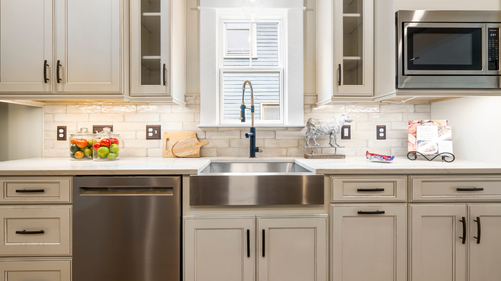 Kitchen with white cabinets, stainless steel sink and appliances, and a window above the sink.