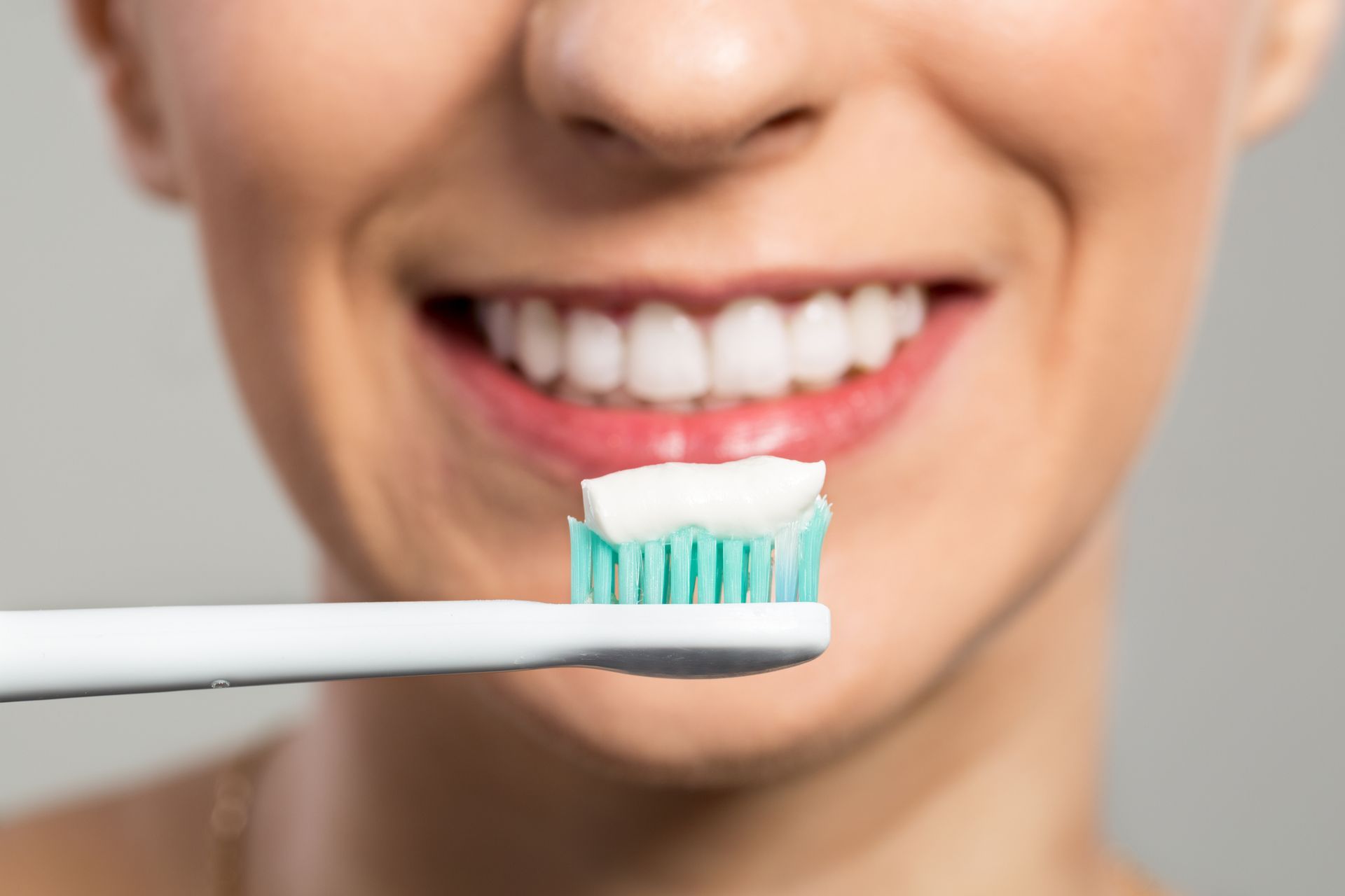 A woman is putting toothpaste on a toothbrush.