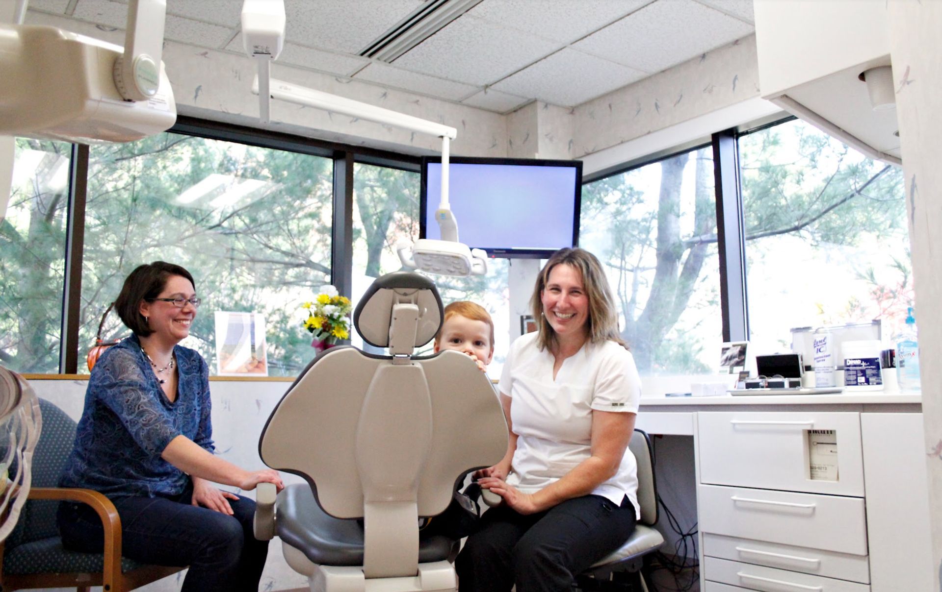 Two women and a child are sitting in a dental chair.