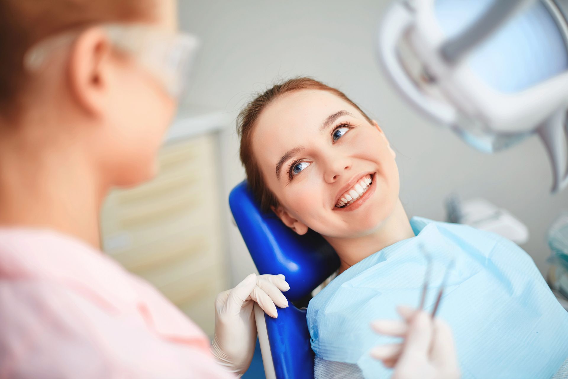 A woman is smiling while sitting in a dental chair.