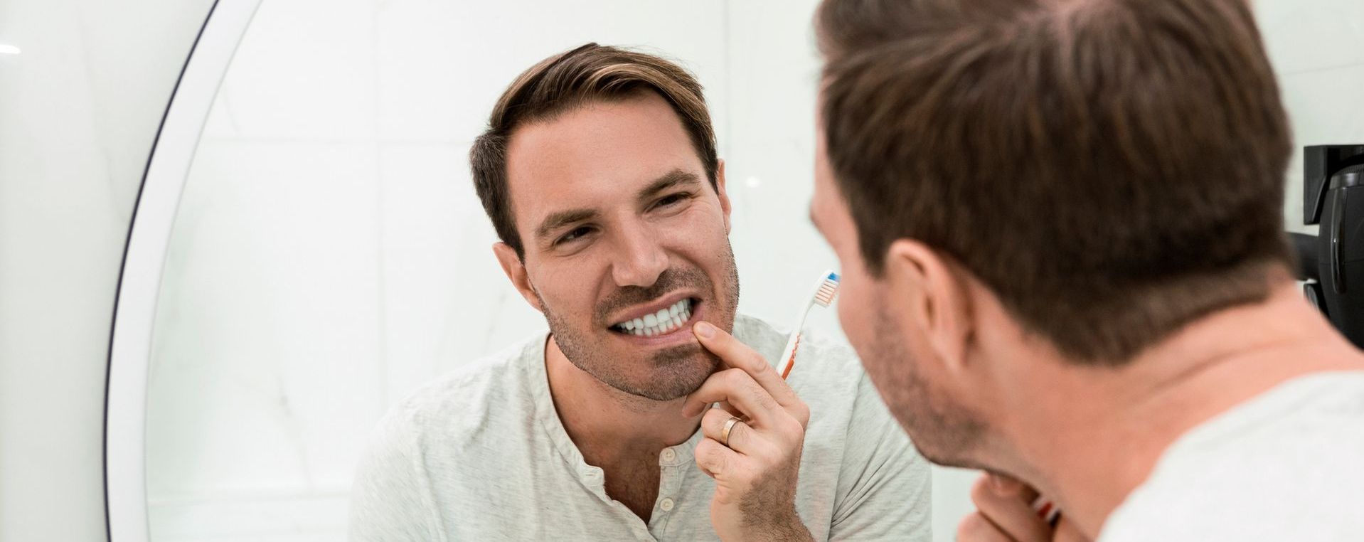 A man is brushing his teeth in front of a mirror.