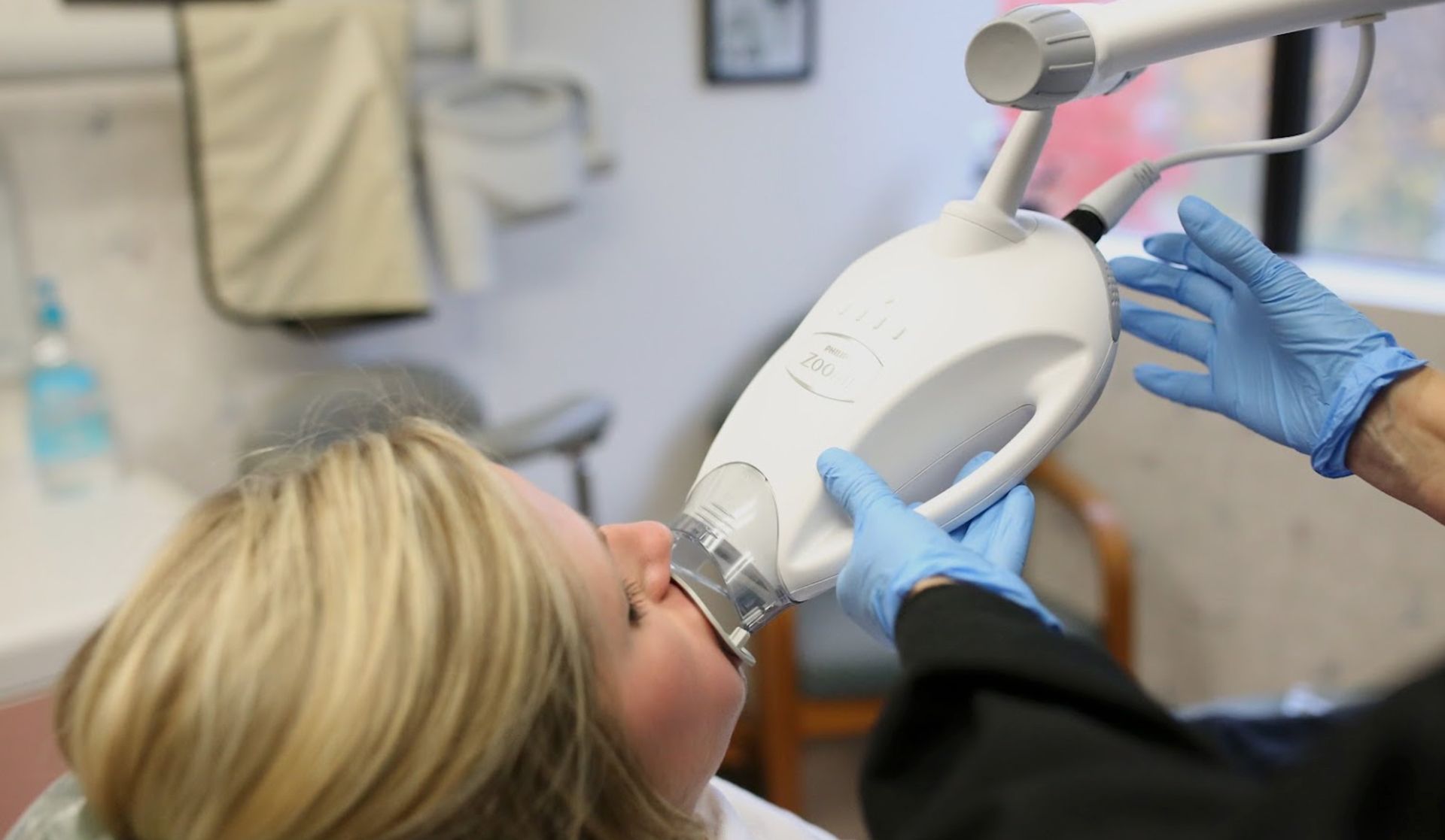 A woman is getting her teeth whitened by a dentist.