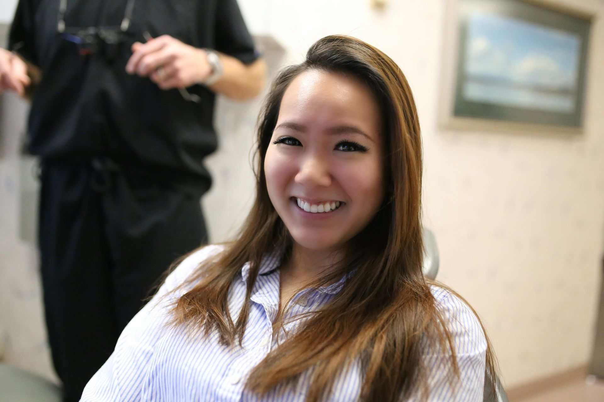 A woman is smiling while sitting in a dental chair