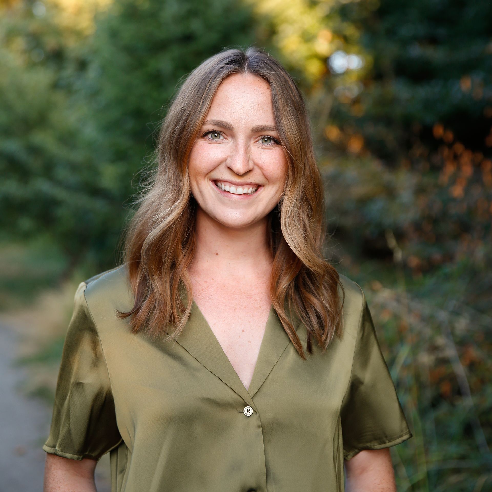 A woman in a green shirt is smiling for the camera.