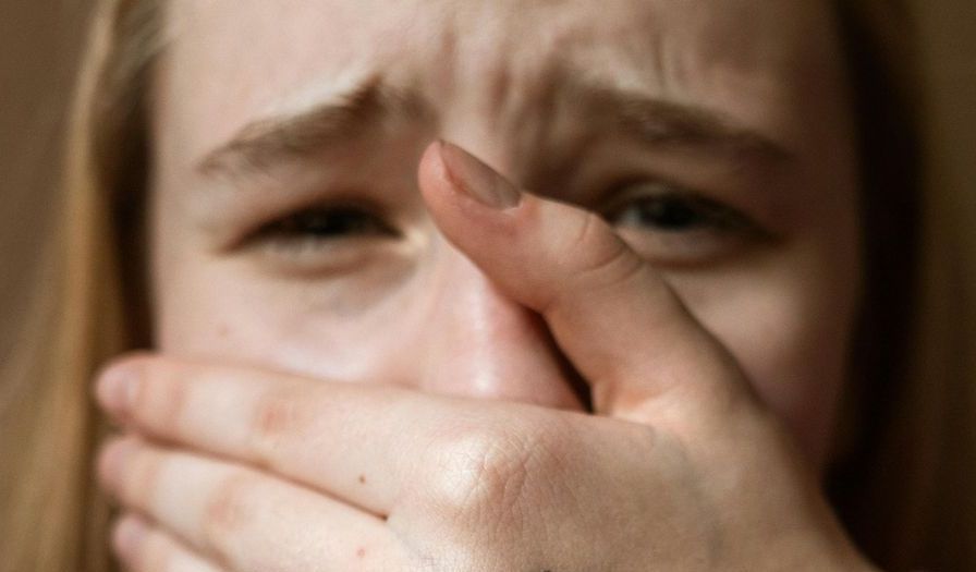 A woman is covering her mouth with her hand.