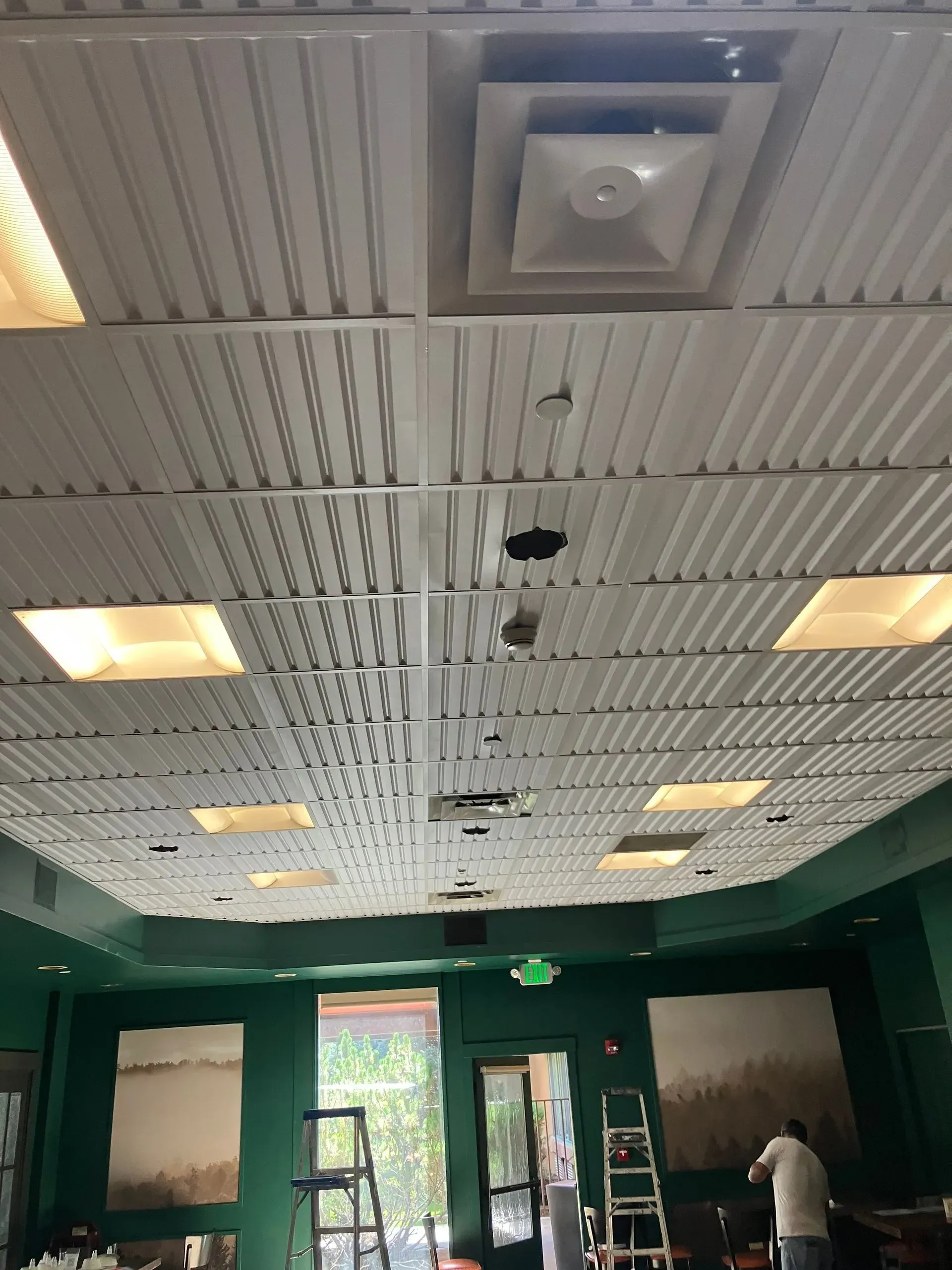 White ceiling meets a wood paneled ceiling with recessed lights, framed by a white border.