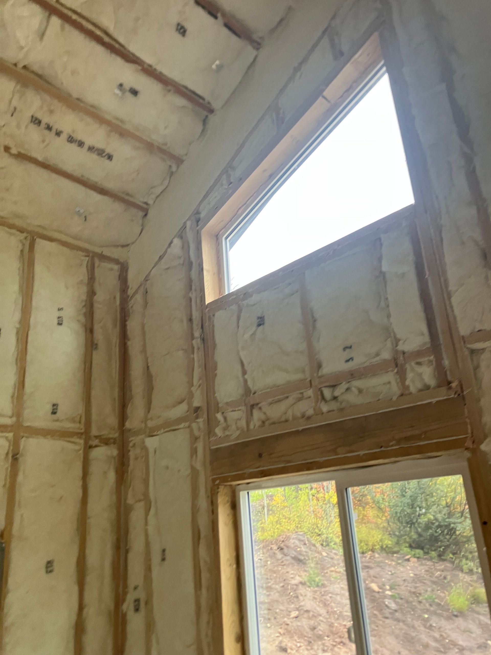 Interior wall of a building under construction, insulated with spray foam. Sunlight through the window.